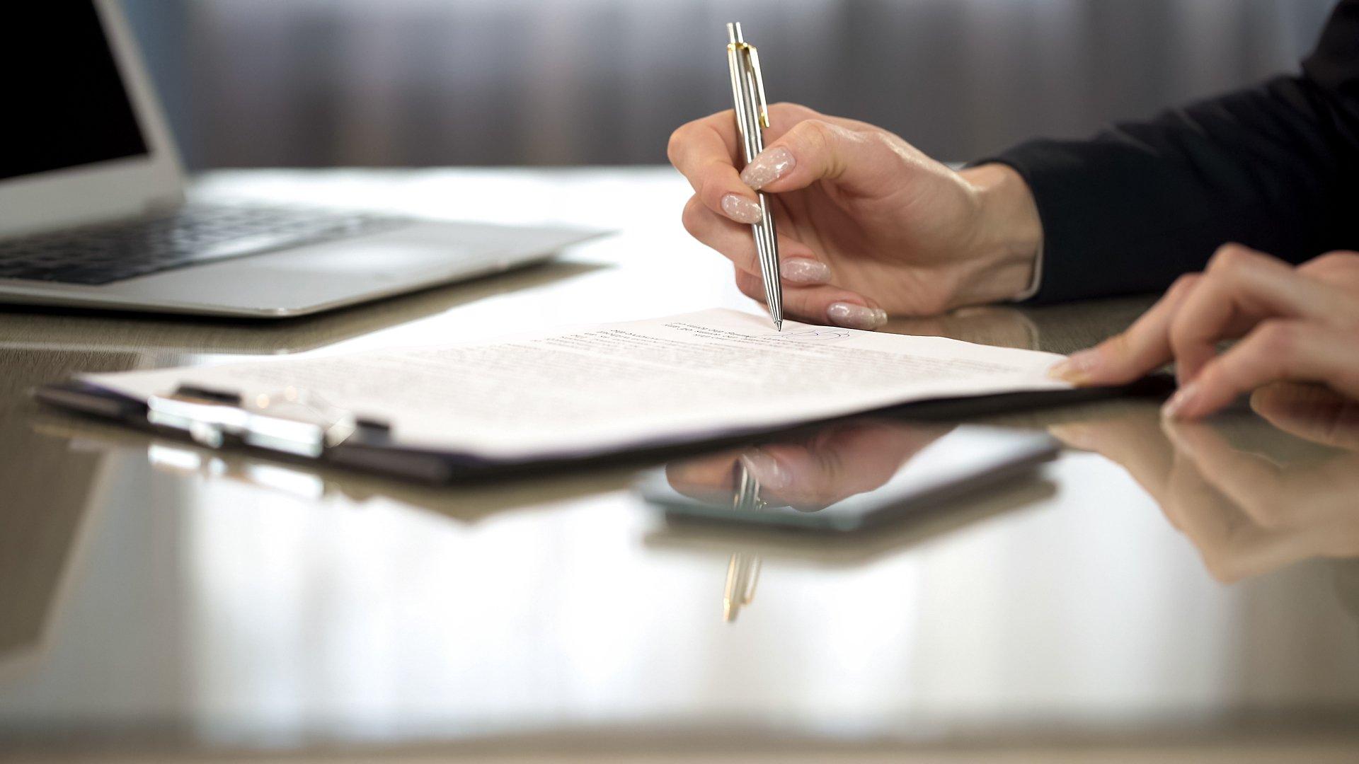 Woman in suit reading terms and conditions of agreement, signing contract