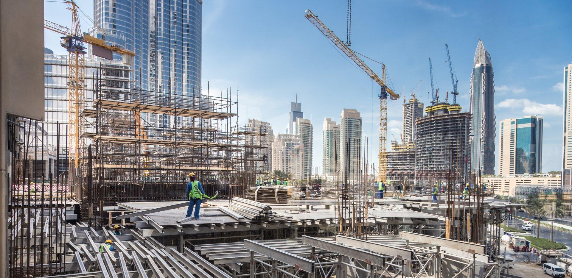 Laborers working on modern constraction site works in Dubai. Fast urban development consept