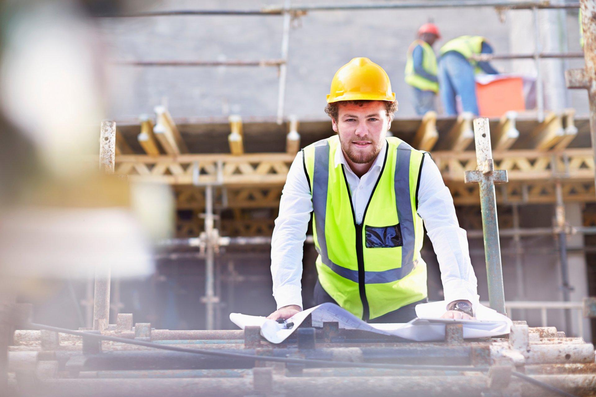 Portrait confident engineer with blueprints at construction site