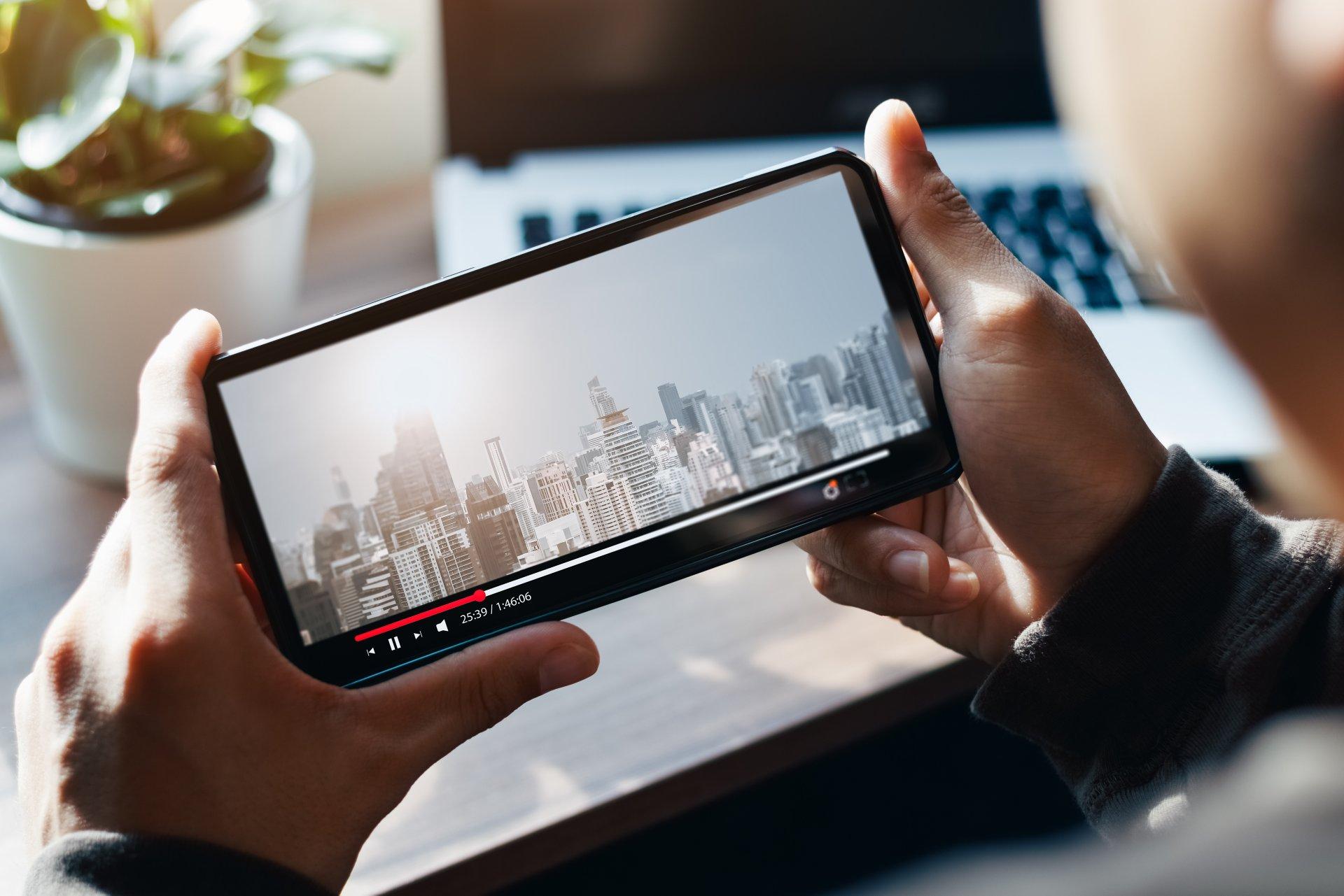 Online movie streaming with smartphone. Young man watching a movie on a mobile phone with an imaginary video player service.