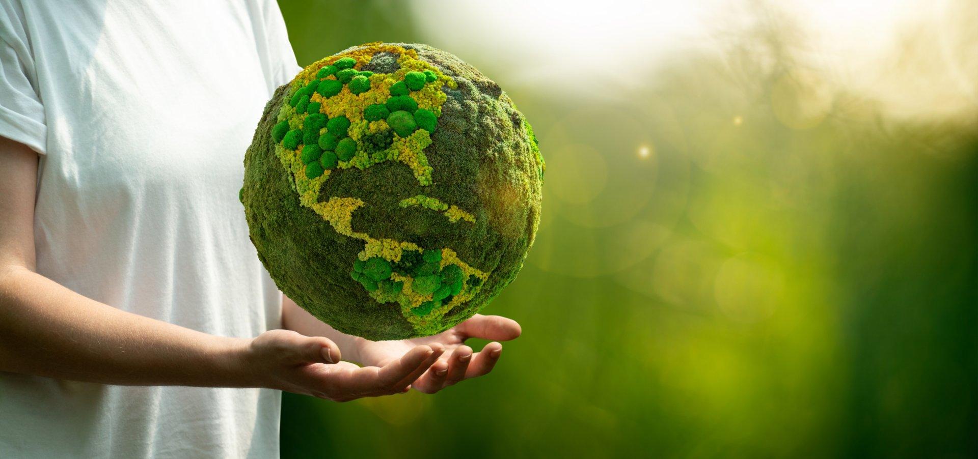 Woman holding a green planet Earth Symbol of sustainable development and renewable energy