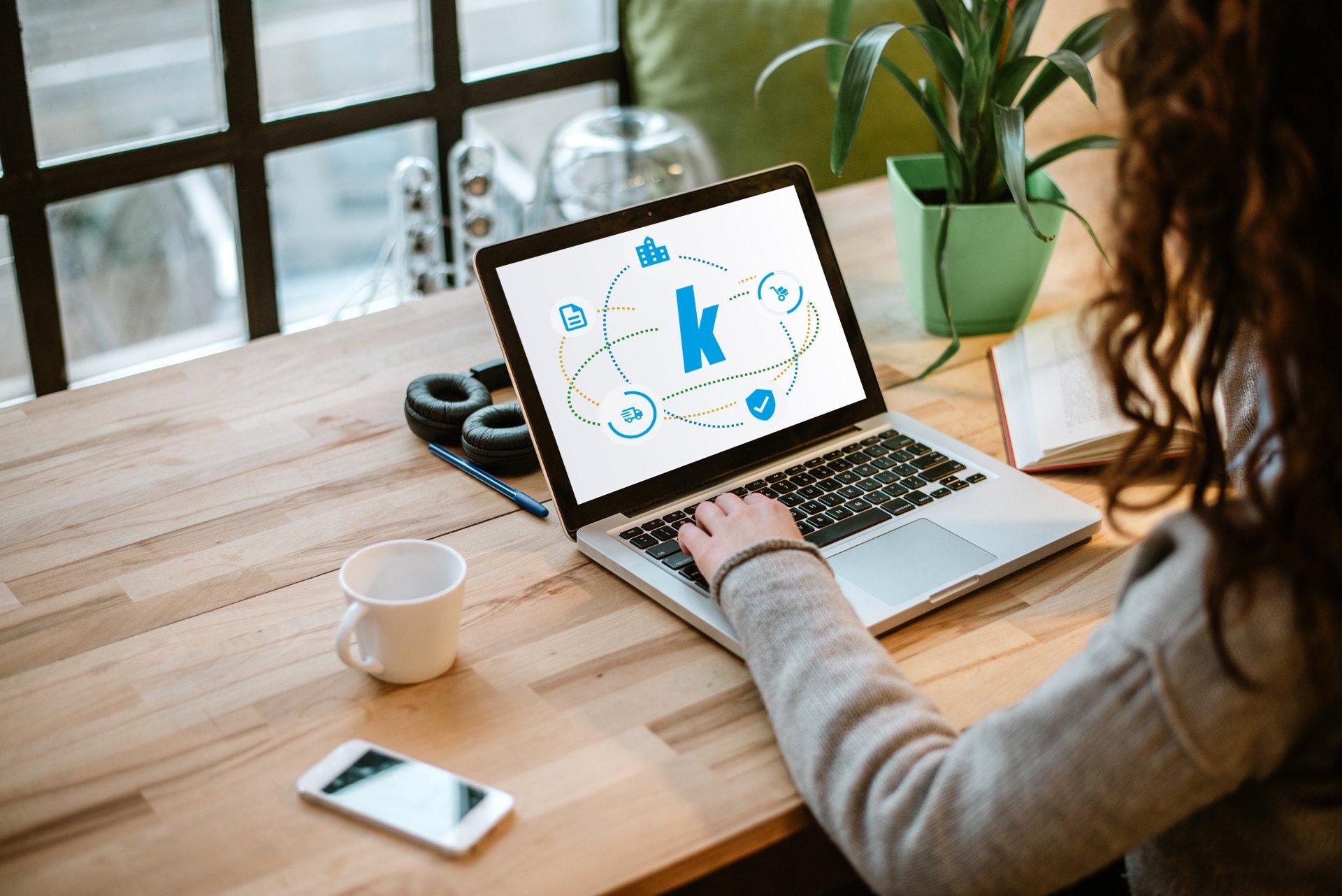 Woman working on laptop with white screen in modern office.